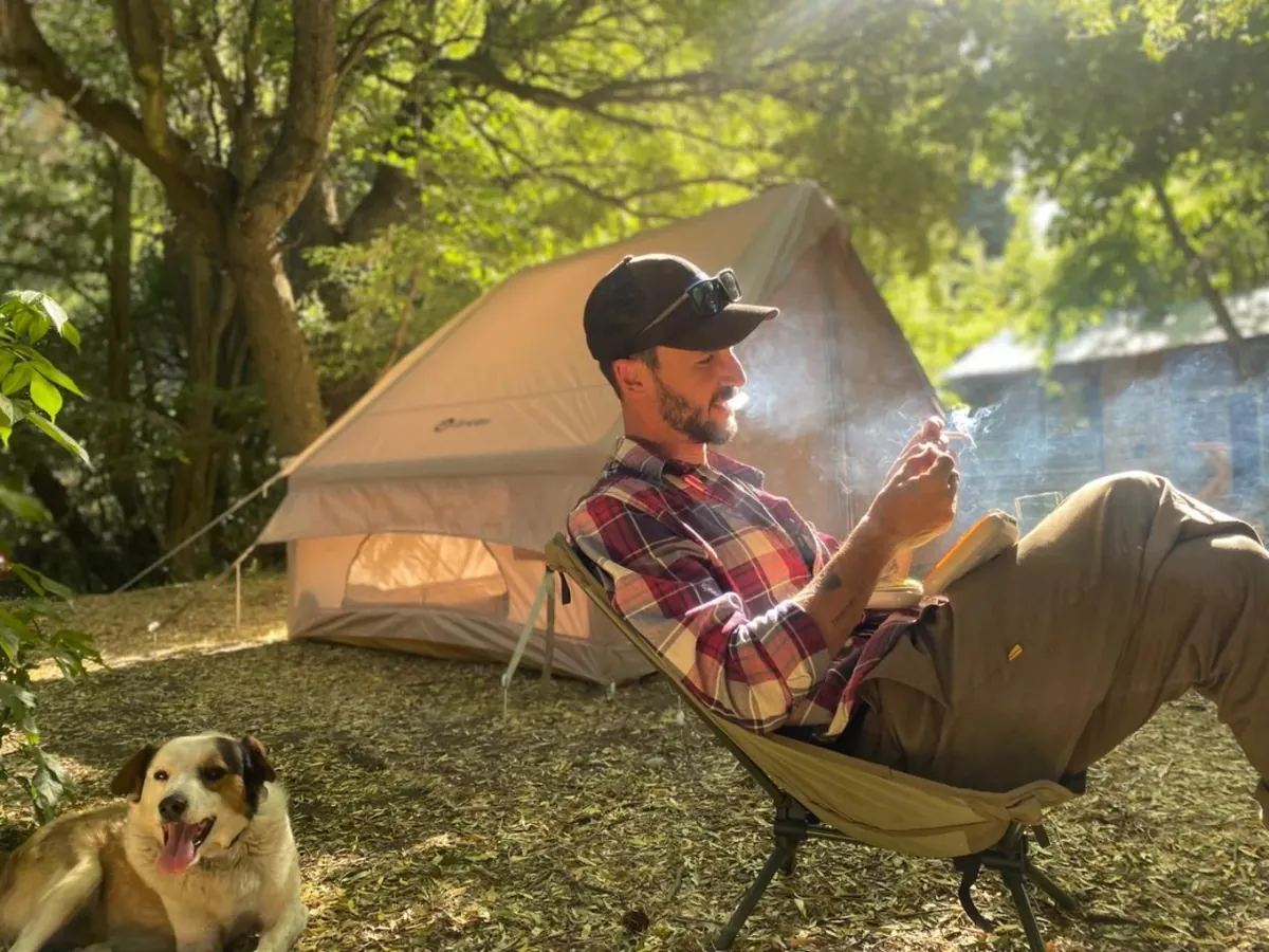Campamento de pesca bajo los árboles con su perro