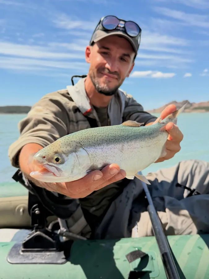 Visitante mostrando una trucha arcoíris pescada en Bariloche
